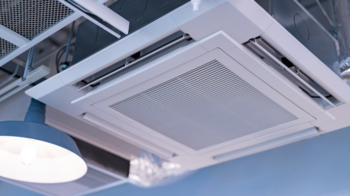ceiling mounted air conditioning unit in commercial venue next to blue lampshade