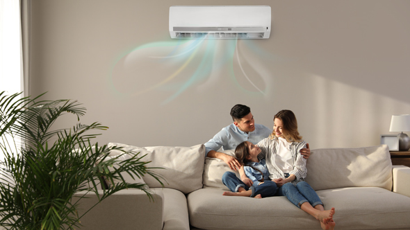 young family sat on beige sofa in living room under air conditioning unit mounted on wall